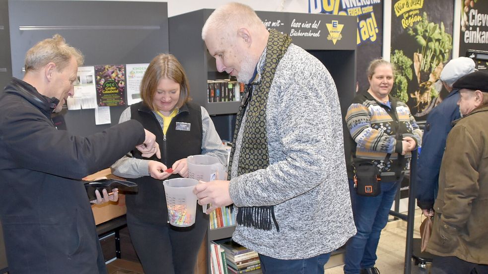 AuchRhauderfehns Bürgermeister Geert Müller (von links), Unternehmerin und Betreiberin des E-Centers, Franziska Schmidt, kauften bei Detlef M. Plaisier, dem Hauptorganisator des 1. Offenen Bücherschrankes, Lose. Der Erlös wird dem Verein Rückenwind gespendet. Foto: Ammermann
