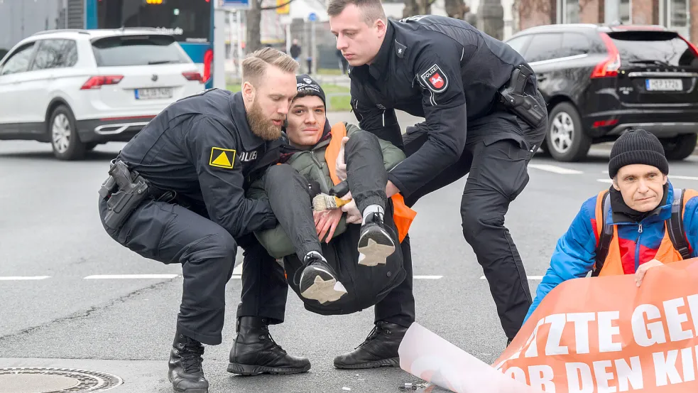 Polizisten tragen festgeklebte Aktivisten der Letzten Generation in Hannover von der Straße: hier Fabian B. aus dem norddeutschen Zeven. Foto: dpa/Julian Stratenschulte