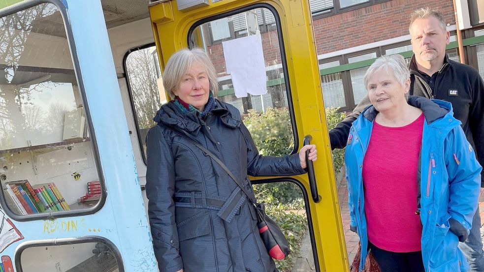 Marina Rex (von links) und Marion Fedder schauten sich am Montagmorgen die Bücherzelle an. Jan Woldenga aus dem Rathaus Rhauderfehn hatte die verrußten Reste am Sonnabend ausgeräumt. Foto: Janßen