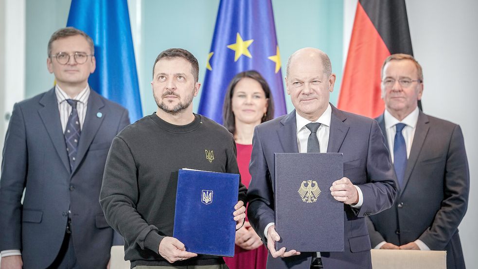 Man steht zusammen: Der ukrainische Präsident Wolodymyr Selenskyj und Bundeskanzler Olaf Scholz überreichen einander das geschlossene Sicherheitsabkommen. Foto: dpa/Kay Nietfeld