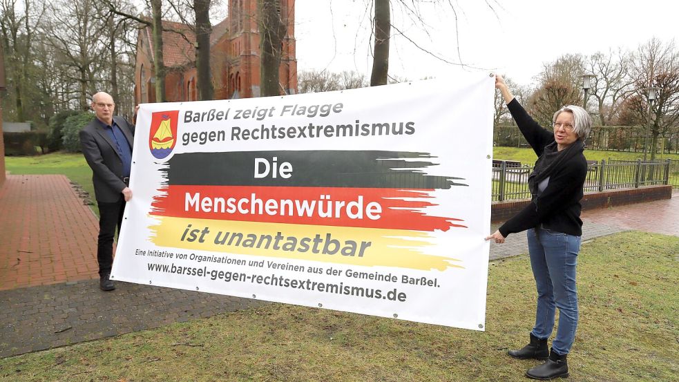 Thomas und Wiebke Perzul präsentieren ein Banner. Davon sollen in den Ortsteilen der Gemeinde Barßel viele aufgehängt werden. Foto: Passmann