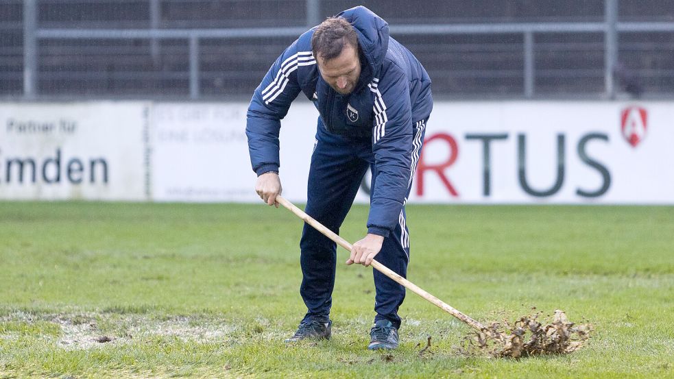 Der Platz in Hannover lässt ein Fußballspiel nicht zu. Auf diesem Foto schiebt Kickers-Co-Trainer Markus Unger vor dem legendären Bersenbrück-Spiel Wasser vom Feld. Foto: Doden, Emden