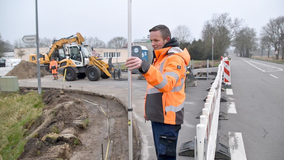 Das Bild zeigt Michael Hoffmann von der Firma HJA beim Einmessen der Baustelle. Für die notwendigen Arbeiten ist die Einmündung von der Bundesstraße in Rhaudermoor in die Schuhmacherstraße gesperrt worden. Foto: Ammermann