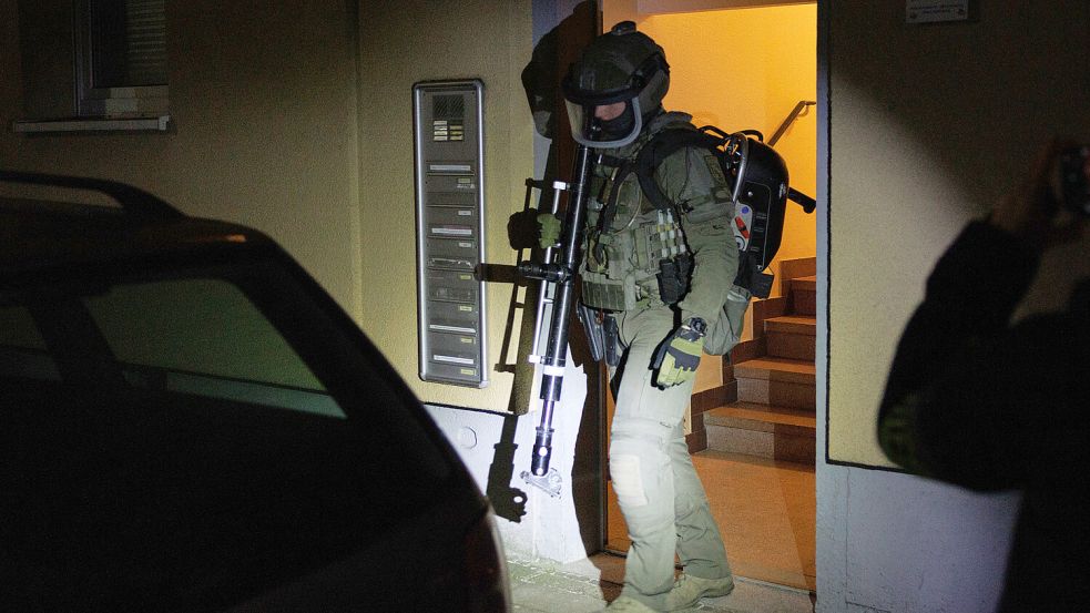 Ein Beamter vom Spezialeinsatzkommando (SEK) kommt aus einem Wohnhaus mit einem Werkzeug zur Türöffnung. Mit einer großangelegten Drogen-Razzia im Westen Niedersachsens und im Großraum Bielefeld hat die Polizei eine professionelle Marihuana-Indoor-Plantage auffliegen lassen. Foto: Friso Gentsch/dpa