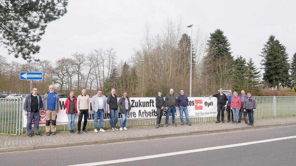 Teile der Belegschaft, Betriebsrat und Gewerkschaft hängten in einer Pausenaktion das Banner am Opti-Werksgelände wieder ab. Vor gut einem Monat hatten sie es dort am Geländer befestigt und auf den Arbeitskampf aufmerksam gemacht. Foto: Kruse