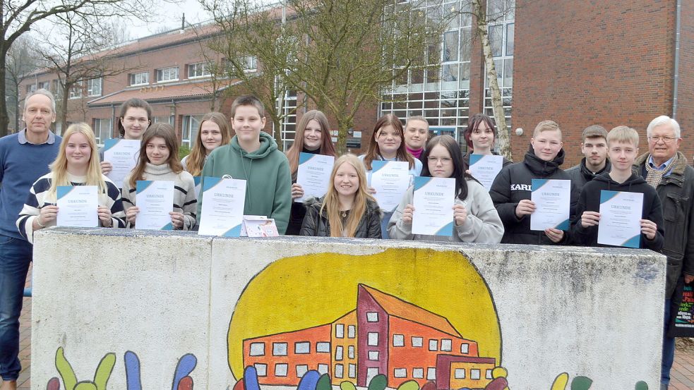 Die neunten und zehnten Klasse der Schule am Osterfehn sammelten fleißig Geld für die Kriegsgräberfürsorge. Das Foto zeigt die Schülerinnen und Schüler mit ihrem Lehrer Torsten Bildhauer (links) sowie mit Kristina Seibel (zehnte von links) und Folkert Laupichler (rechts) vom Volksbund Deutsche Kriegsgräberfürsorge. Foto: Weers