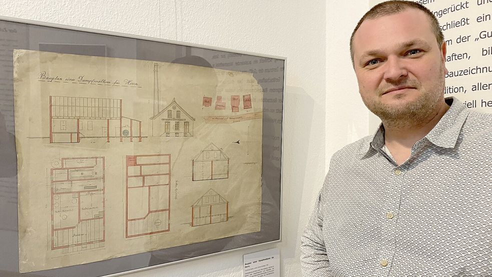 Museumsleiter Markus Neumann steht neben der Bauskizze der Dampfmolkerei Rhaudermoor von 1908. Foto: Löschen