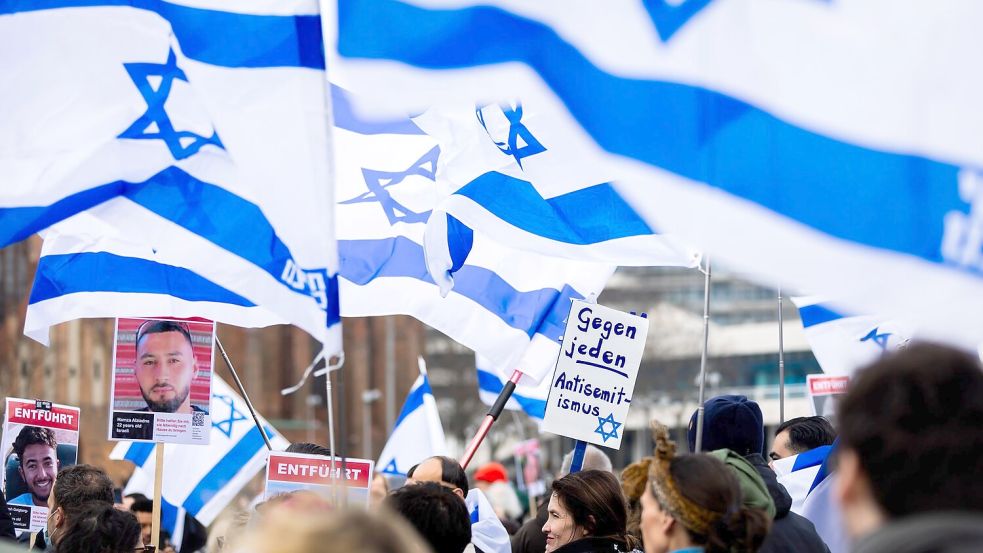 Menschen demonstrieren in Berlin mit Israelischen Fahnen gegen Antisemitismus und für Solidarität mit Israel. Foto: Christoph Soeder/dpa