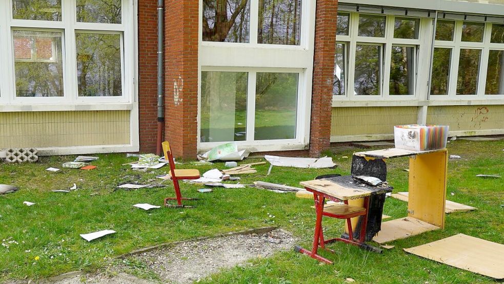 Überbleibsel des Brandes stehen auf der Grünfläche neben dem Schulgebäude. Ein verkohlter Schrank und ein Schultisch samt Stuhl sowie diverse Unterlagen und Zettel wurden nach draußen befördert. Foto: Roispich
