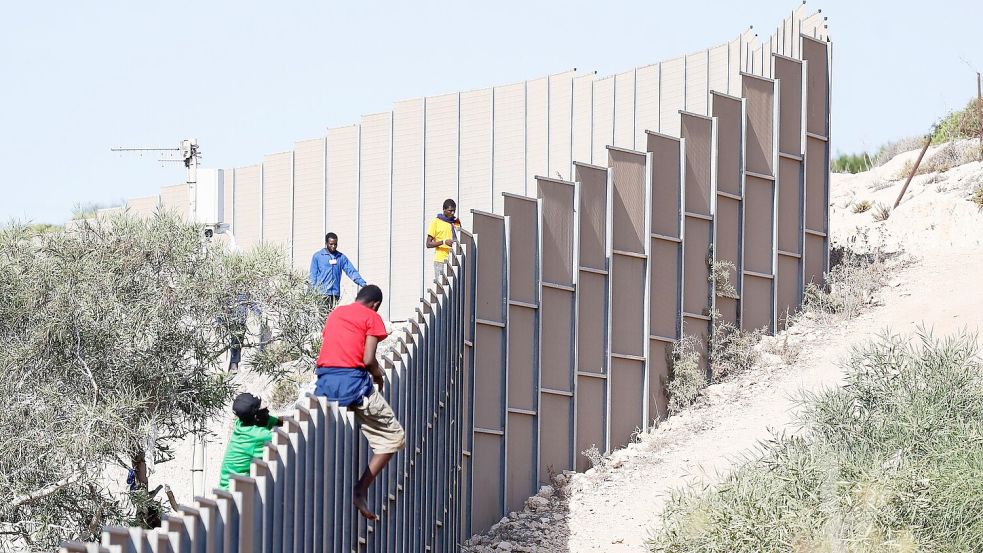 Migranten klettern über einen Zaun auf der Insel Lampedusa. Foto: Cecilia Fabiano/LaPresse via ZUMA Press/dpa
