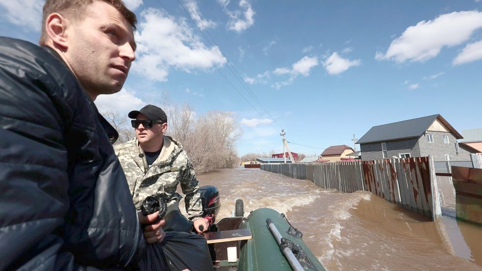 Anwohner fahren in ihrem Schlauchboot, um bei der Evakuierung von Menschen in Orenburg zu helfen. Foto: Uncredited/AP/dpa