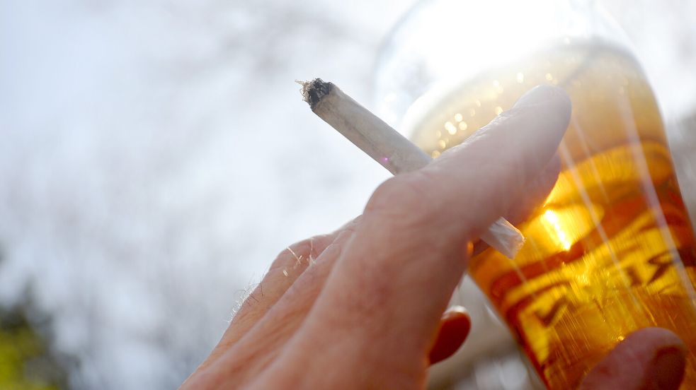 Eine Hand hält einen Joint neben einem Bierglas. Grundsätzlich ist der Cannabis-Konsum auch in Biergärten seit Anfang April erlaubt. Foto: Hildenbrand/DPA