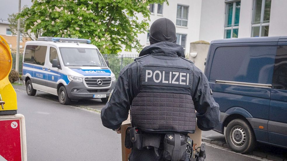 Ein Polizist trägt bei einem Einsatz in Bonn einen Karton mit beschlagnahmtem Material aus einem Gebäude. Foto: Benjamin Westhoff/dpa