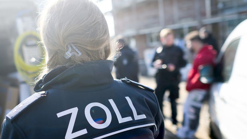 Zollbeamte stehen mit Bauarbeitern bei einer Kontrolle von Schwarzarbeit in einem Neubaugebiet. Foto: Stratenschulte/DPA