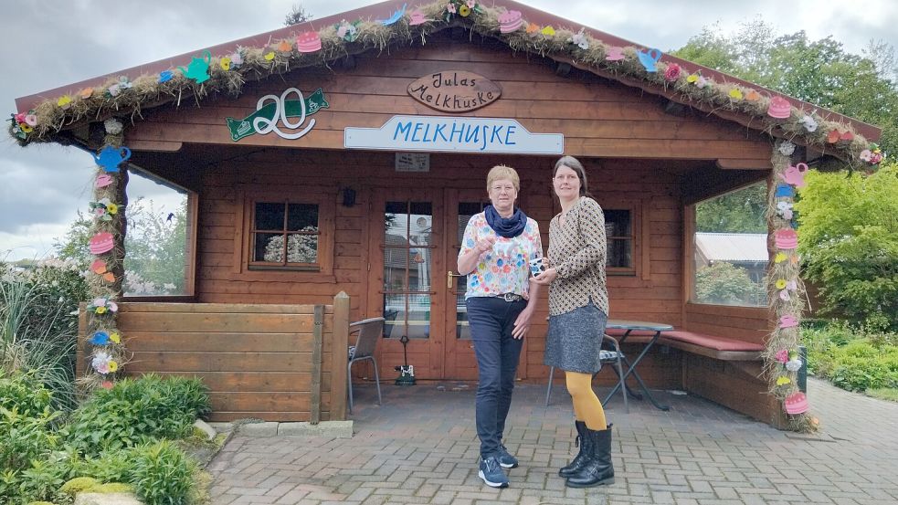 Zum 20. Jubiläum schmückten die Nachbarn das Melkhuske mit einem bunten Bogen. Jula (links) und Gunda Weers freuen sich sehr. Foto: Scherzer