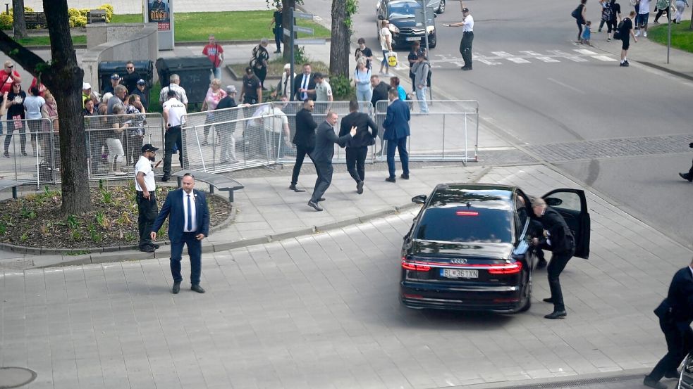 Leibwächter bringen den slowakischen Ministerpräsidenten Robert Fico in einem Auto vom Ort des Geschehens in Sicherheit. Foto: Radovan Stoklasa/TASR/dpa