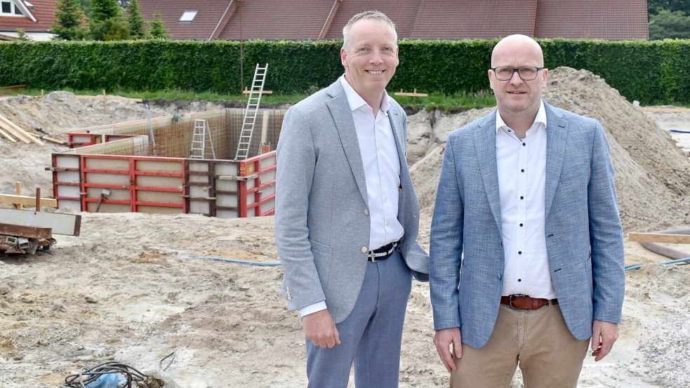 Die Vorstandsmitglieder der Volksbank Westrhauderfehn, Uwe Brechtezende (links) und Kai Stöter, stehen vor dem Neubauprojekt an der Beethovenstraße. Im Hintergrund ist bereits der Keller zu sehen. Foto: Zein