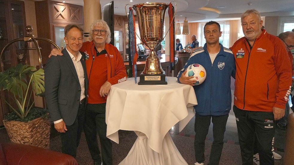 „Losfee“ Andreas Meinders (von links, Firma OrgaData/Premiumpartner), Ewald Adden (Organisator), „Losfee“ Thorsten Lettau (TuS Holtriem) und Manfred Bloem (Organisator) posieren neben dem Siegerpokal. Foto: Steenhoff