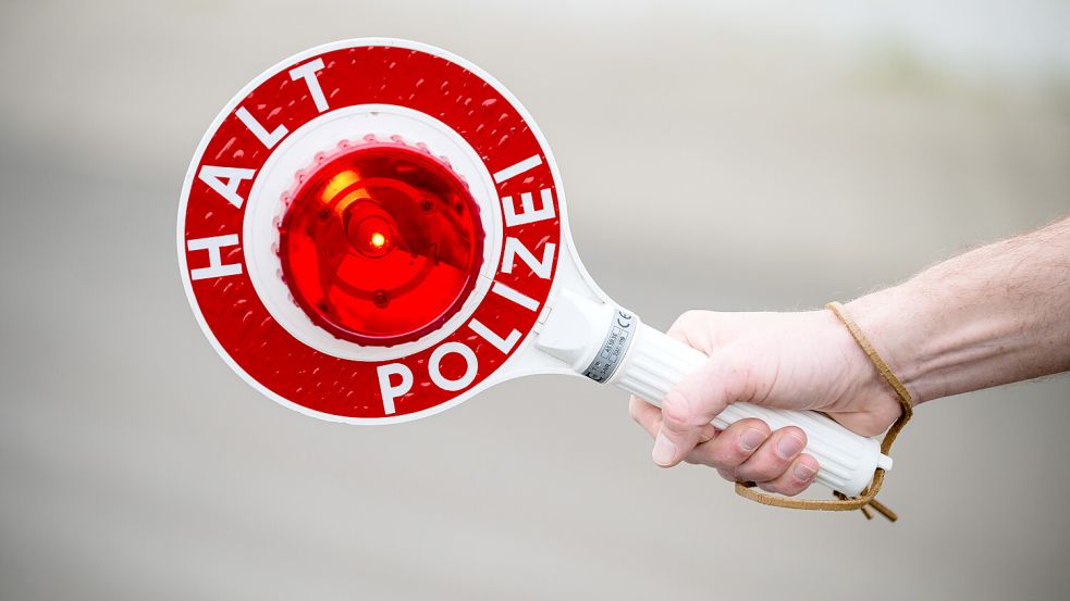 Ein Polizist hält eine Kelle mit der Aufschrift „Halt Polizei“ in der Hand. Foto: DPA