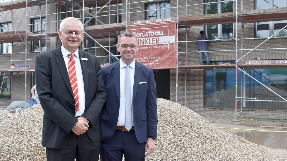 Frank Fastenau (links) und Ingo Fortkamp von der Sparkasse Leer-Wittmund stehen an der Hauptstraße in Ostrhauderfehn vor dem Neubau, in dem im Erdgeschoss die Sparkasse einziehen wird.