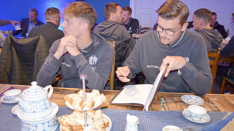 Beim Teetrinken ging das Goldene Buch der Gemeinde Rhauderfehn durch die Reihen der Fußballer. Hier trägt sich Bennet Schmidt ein (rechts), vor ihm war Adrian Lenz dran. Foto: Fertig