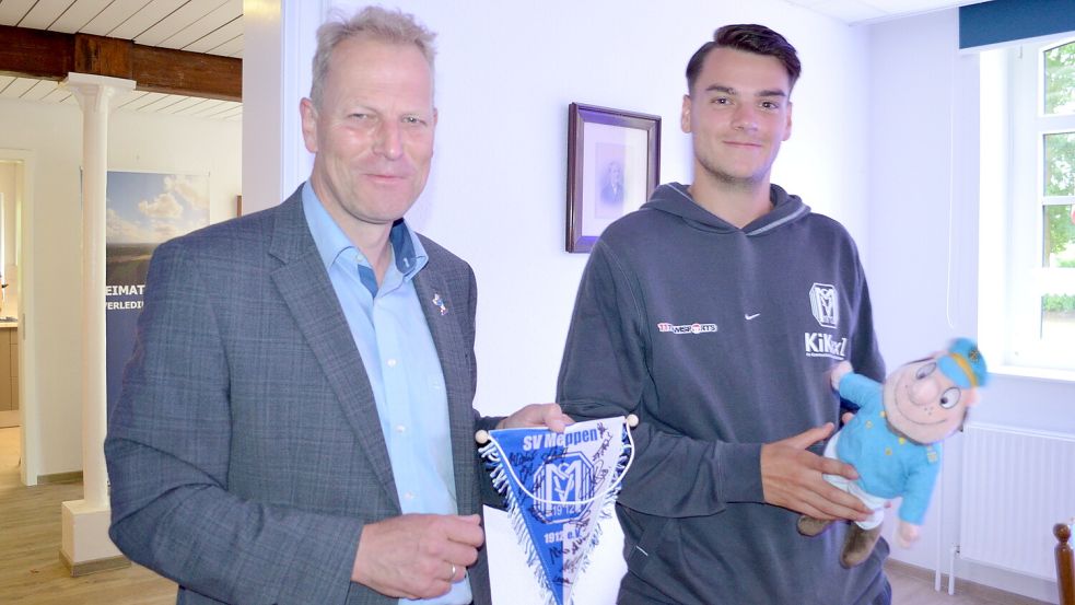 Geschenke wurden ausgetauscht: Rhauderfehns Bürgermeister Geert Müller (links) freut sich über einen Wimpel in den Vereinsfarben des SV Meppen mit Unterschriften aller Spieler der 1. Herrenmannschaft. Dessen Kapitän Jonas Fedl erhielt vom Rhauderfehner Bürgermeister eine Plüschfigur des Gemeindemaskottchens Fokko vom Fehn. Foto: Fertig