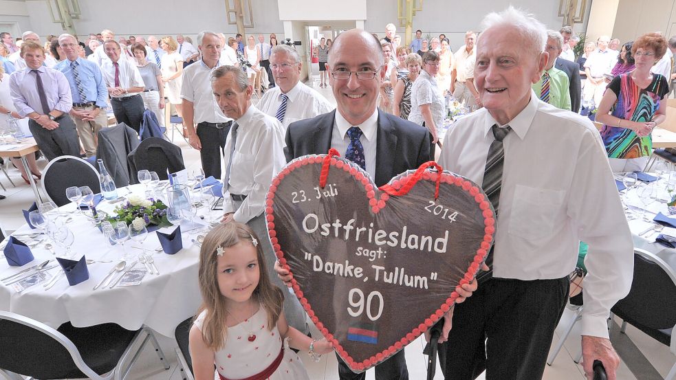 Klaus Peters (Mitte), Leiter der Gesamtproduktion bei Enercon, hielt die Rede zu Rolf Trauernichts 90. Geburtstag am 23. Juli 2014 und überreichte ihm mit Tochter Lilly (links) ein großes Lebkuchenherz. Foto: Archiv/Ortgies