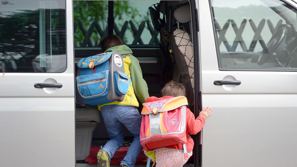 Schulkinder steigen in ein Auto. Foto: Hirschberger/dpa