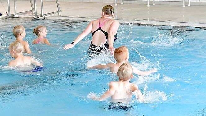 Vor dem Schwimmtraining machen sich die Trainerinnen gemeinsam mit den Kindern mit Wasserübungen warm. Foto: Wagenaar