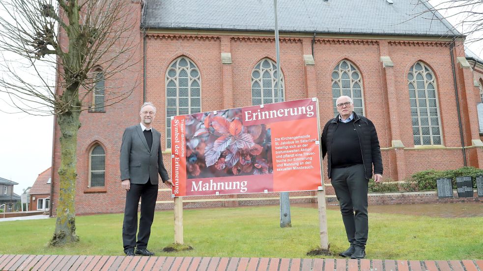Vor der St.Jakobus-Kirche wird eine Trauer-Blutbuche gepflanzt und eine Stele aufgestellt. Pfarrer Ludger Fischer (links) und Pfarreiratsvorsitzender Georg Pugge haben ein Transparent aufgestellt. Foto: Passmann