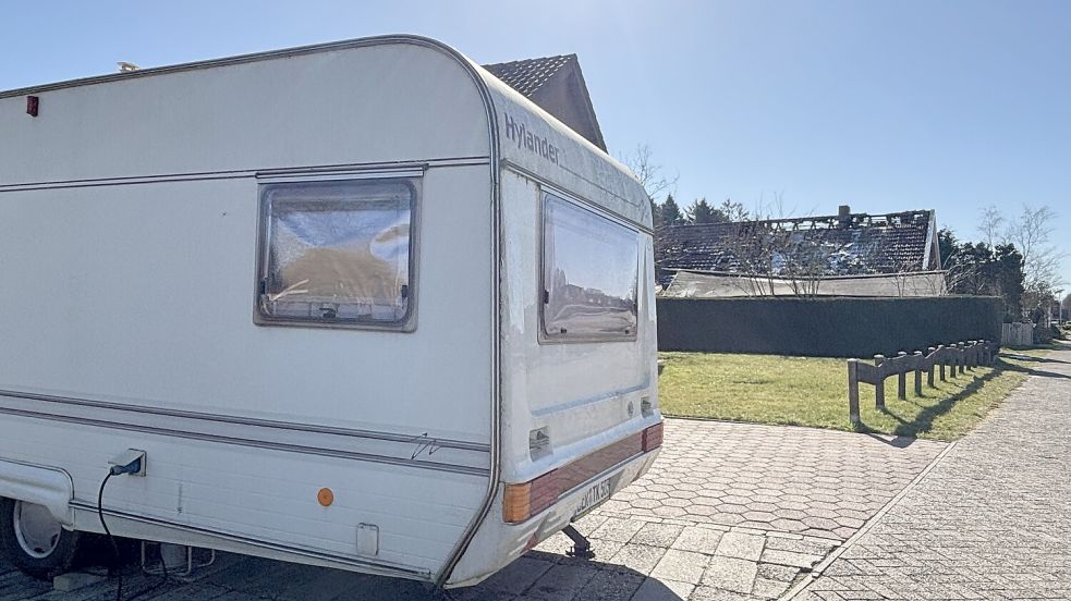 Nach dem Feuer lebt Bewohnerin Tanja Kampen mit ihren Hunden in einem Wohnwagen. Im Hintergrund ist das beschädigte Wohnhaus zu sehen. Foto: Zein