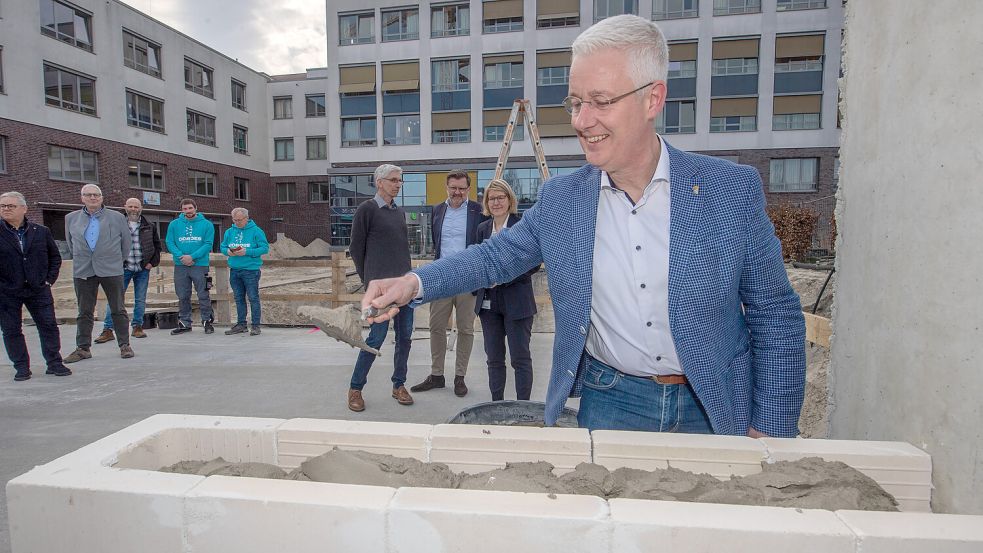 Landrat Matthias Groote half beim Einmauern der Zeitkapsel. Foto: Ortgies