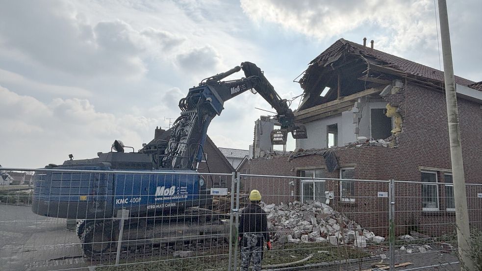 Mithilfe eines großen Baggers wird das Gebäude dem Erdboden gleich gemacht.