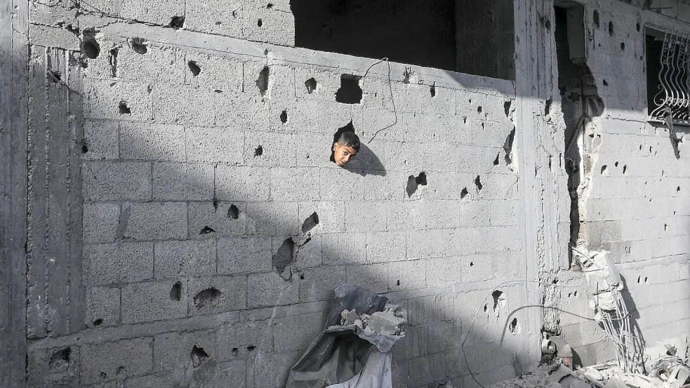 Ein palästinensisches Kind schaut aus einem Loch in einem Gebäude in Chan Junis, das durch einen israelischen Luftangriff beschädigt wurde Foto: Abed Rahim Khatib/dpa