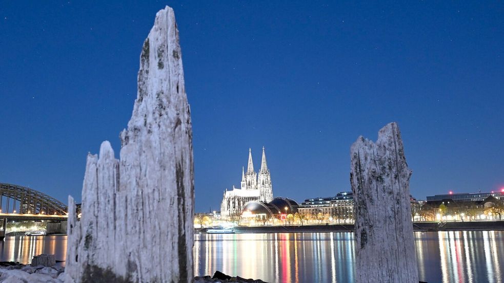 Teile einer Holzkonstruktion, die normalerweise unter Wasser liegen, sind am Rhein gegenüber vom Kölner Dom zu sehen. Foto: Federico Gambarini/dpa