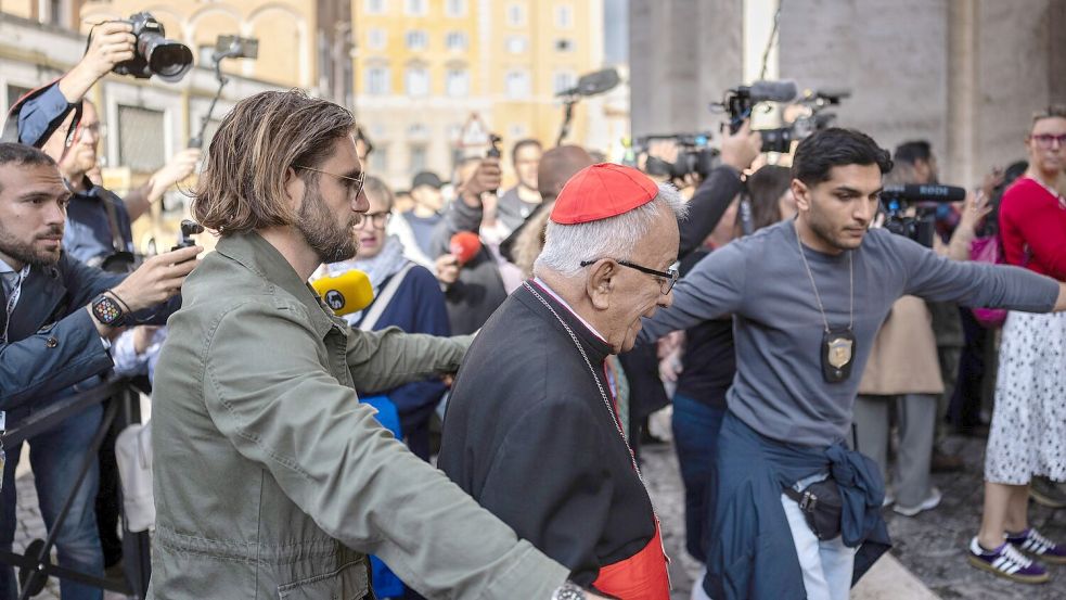 Auf dem Weg zum Vatikan kämpfen sich die Kardinäle durch eine Menge aus Journalisten und Schaulustigen. Foto: Oliver Weiken/dpa