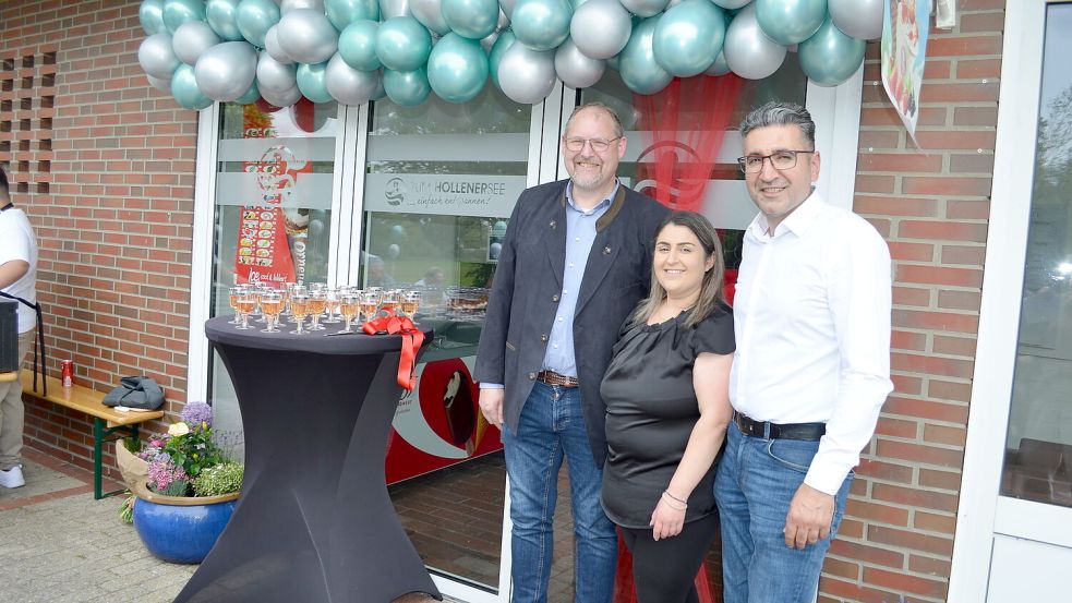 Mit Sekt, Blumen und Luftballons wurde der Kiosk „Zum Hollener See“ am Sonnabend, 31. Mai 2025, wiedereröffnet. Saterlands Bürgermeister Thomas Otto (links) wünschte den neuen Betreibern, Keziban (Mitte) und Erol Berisik, alles Gute. Foto: Astrid Fertig