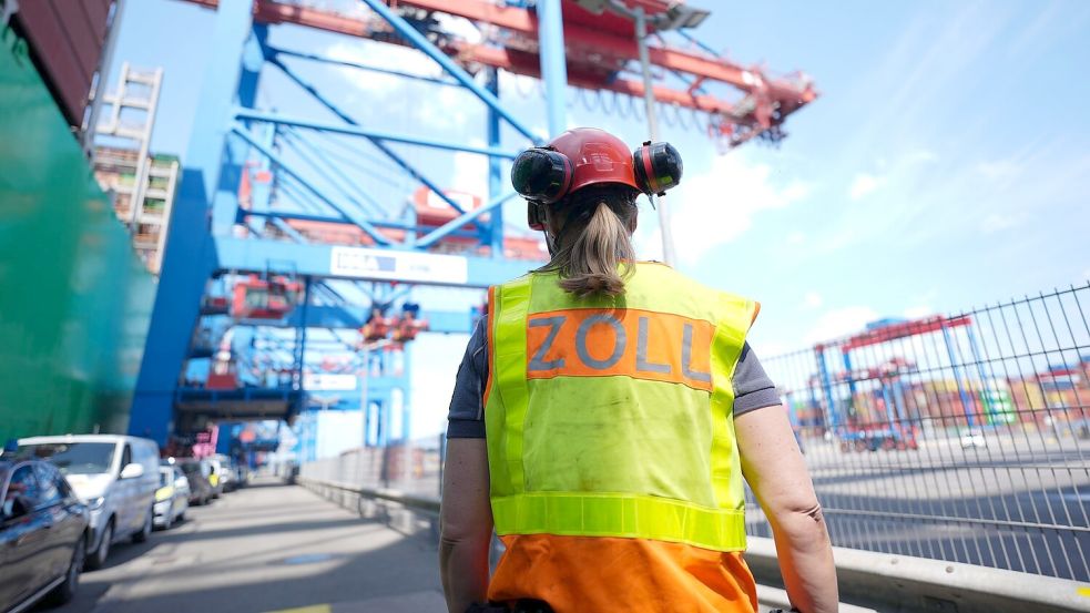 Eine Zollbeamtin steht neben einem Containerschiff im Hamburger Hafen. Foto: Marcus Brandt/dpa