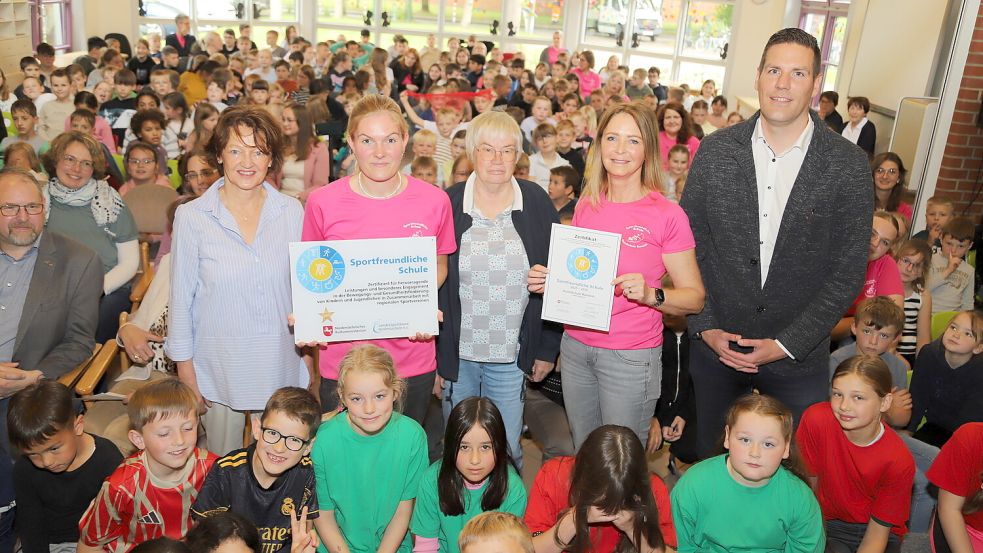 Inmitten der Kinder freuen sich Dezernentin Heike Böttjer (von links), Laura Schröder (Fachleitung Sport) Birgit Beintken (KSB), Ulrike Rieger (stellvertretende Schulleiterin) und Christoffer Melzer (Fachberater Sport) über das Zertifikat „Sportfreundliche Schule“. Foto: C. Passmann