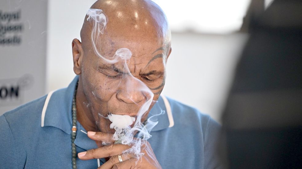 Box-Ikone und Cannabis-Unternehmer Mike Tyson raucht an einem Stand der Cannabis-Messe Mary Jane einen Joint. Foto: Sebastian Gollnow/dpa