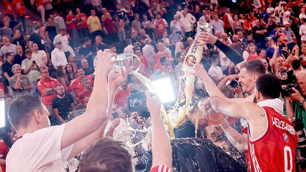 Die Bayern-Basketballer überschütten Coach Herbert mit Bier. Foto: Matthias Stickel/dpa