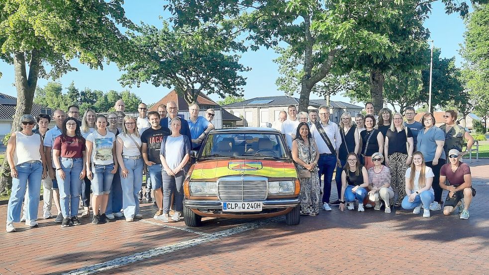 Das Foto zeigt Uwe Schlüsselburg und seine Frau Gloria (vorne rechts neben dem Fahrzeug), die sich über die gelungene Überraschung der Kolleginnen und Kollegen freuen. Foto: Gemeinde/Waden