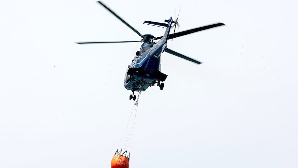 Ein Löschhubschrauber der Bundespolizei fliegt über dem Zeithainer Tagebau und nimmt Wasser auf, um den Waldbrand Gohrischheide zu bekämpfen. Foto: Daniel Wagner/dpa