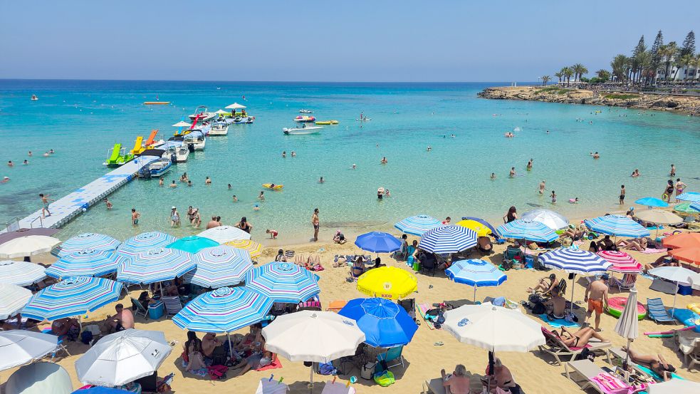 Touristen entspannen an einem Strand auf der Mittelmeerinsel Zypern. Foto: IMAGO/Zoonar
