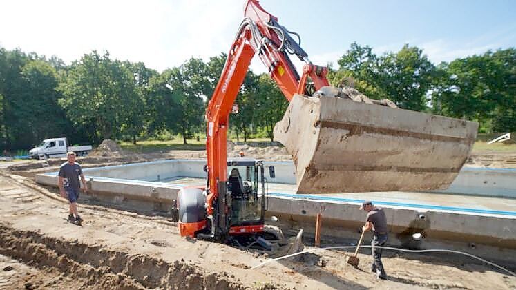 Der Bagger schafft derzeit Platz für die neuen Wasserleitungen zum 50 Meter langen Schwimmbecken. Foto: Mirco Moormann