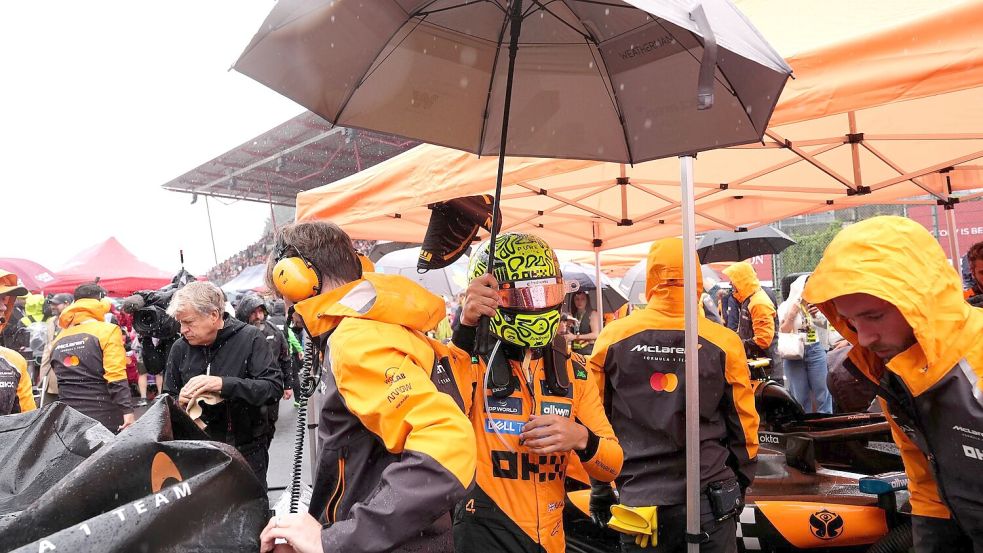 Die Fahrer wurden während der Unterbrechung mit Schirmen vor dem Regen geschützt. Foto: Bradley Collyer/PA Wire/dpa