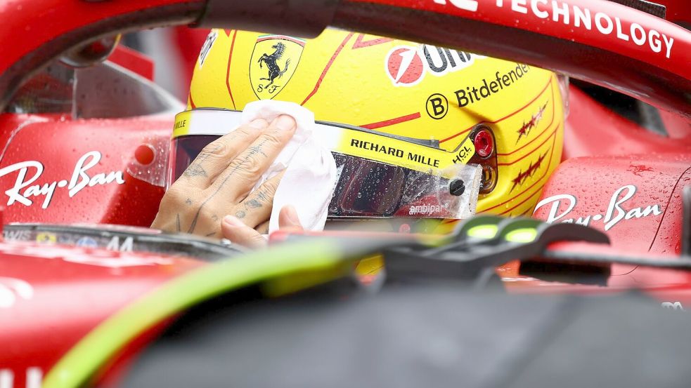 Lewis Hamilton wischt sich den Regen vom Visier. Foto: Yves Herman/Pool Reuters/AP/dpa