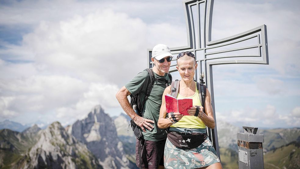 Patrick and Cathy, beide 58, lesen im „Berg-Tinder“-Notizbuch auf dem Gipfel des Wandflue. Foto: Gabriel Monnet/AFP