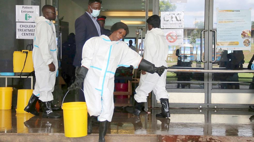 Eine Mitarbeiterin trägt Desinfektionsmittel aus einem Cholera-Behandlungszentrum (Archivbild) Foto: --/AP/dpa