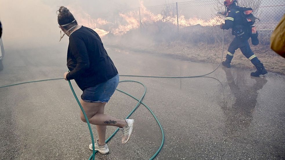 Bewohner und Feuerwehrleute bekämpfen die Flammen. Foto: Marios Lolos/XinHua/dpa